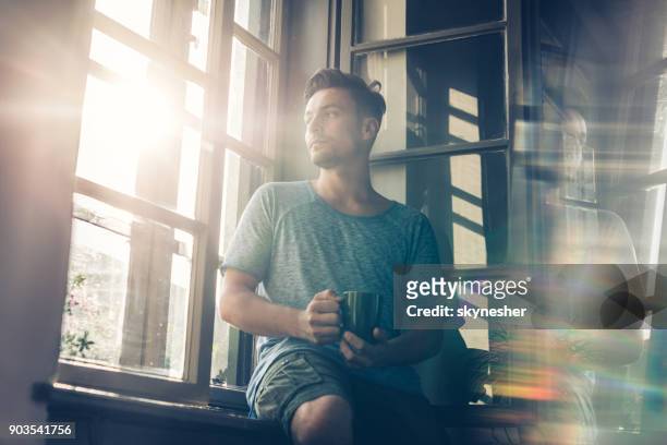 below view of pensive man with coffee cup by the window. - casual room imagens e fotografias de stock