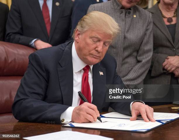 President Donald Trump signs a bipartisan bill to stop the flow of opioids into the United States in the Oval Office of the White House on January...