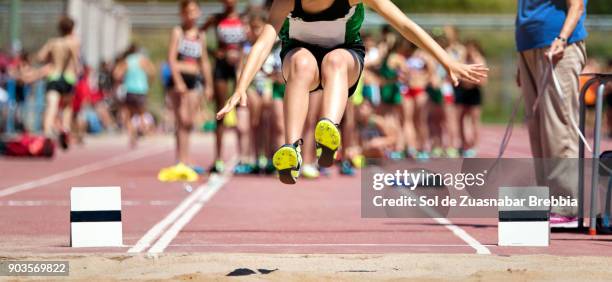 close-up of the legs of a girl flying on the sand in long jump - kids track and field stock pictures, royalty-free photos & images