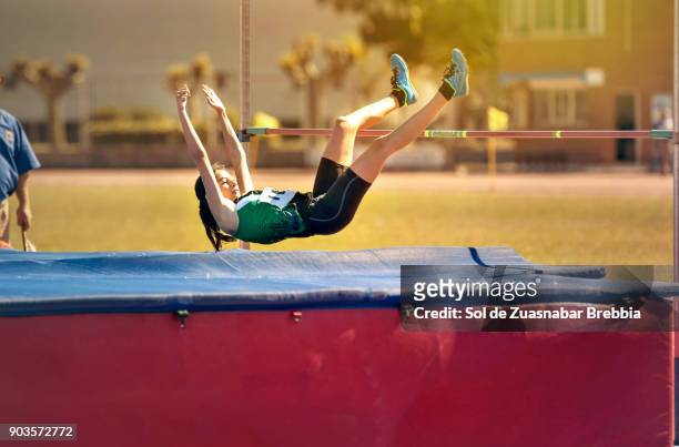 brunette teen girl doing high jump in a sunny day - courses in santander fotografías e imágenes de stock
