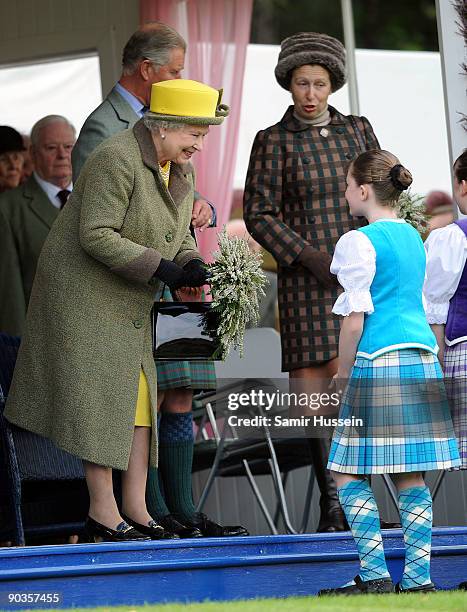 Queen Elizabeth II and Princess Anne, Princess Royal accept flowers as they attend the 2009 Braemar Highland Games on September 5, 2009 in Braemar,...