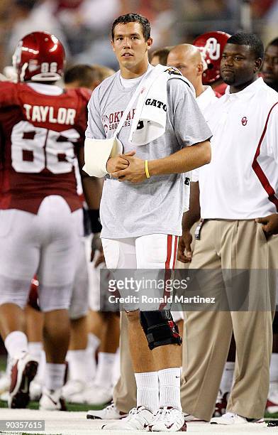 Quarterback Sam Bradford of the Oklahoma Sooners stands on the sidelines after suffering an injury against the Brigham Young Cougars at Cowboys...