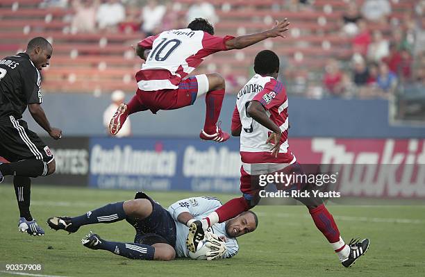 David Ferreira of the FC Dallas leaps over goalie Josh Wicks of the DC United as he blocks the ball while Jeff Cunningham of the FC Dallas looks on...