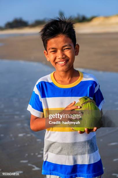 vietnamese boy holding coconuts on the beach, vietnam - vietnam strand stock pictures, royalty-free photos & images