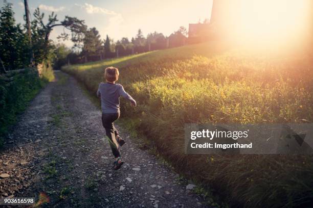 happy boy running on rural path - boy running back stock pictures, royalty-free photos & images