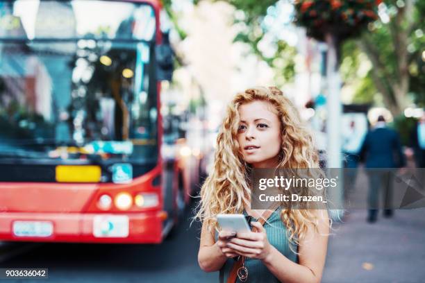 frau, mit mobilen app auf bushaltestelle - sydney buses stock-fotos und bilder