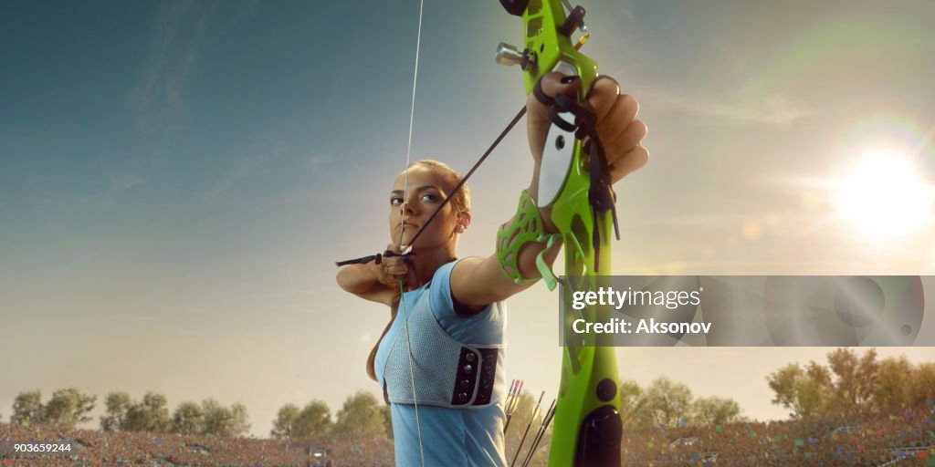 Female archer shooting with the longbow at sunset