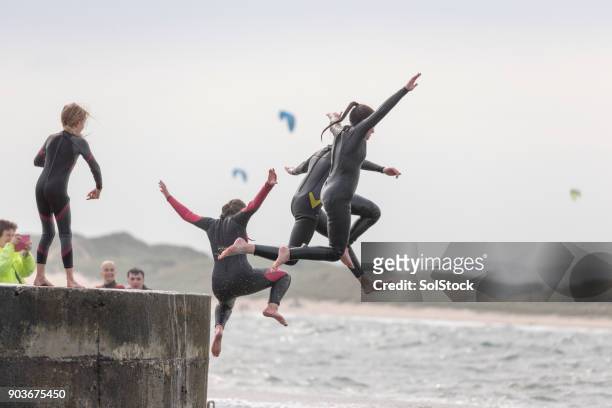 jumping from the harbour - beach family jumping stock pictures, royalty-free photos & images
