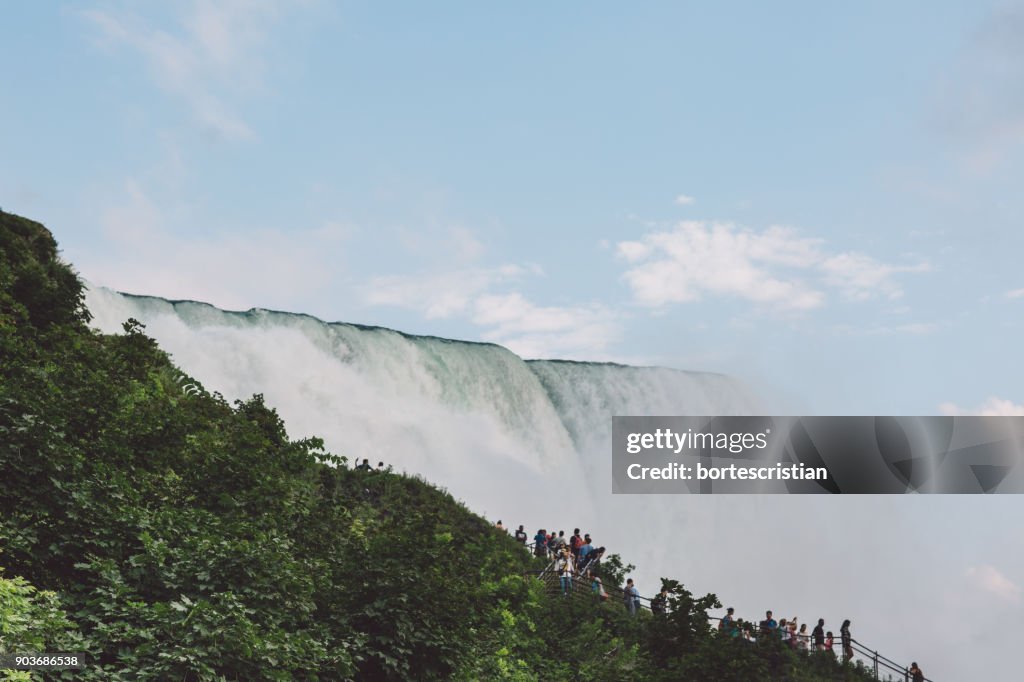 People By Waterfall Against Sky