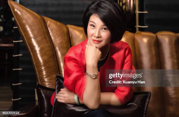 mature chinese businesswoman sitting on sofa - china middle class photos et images de collection