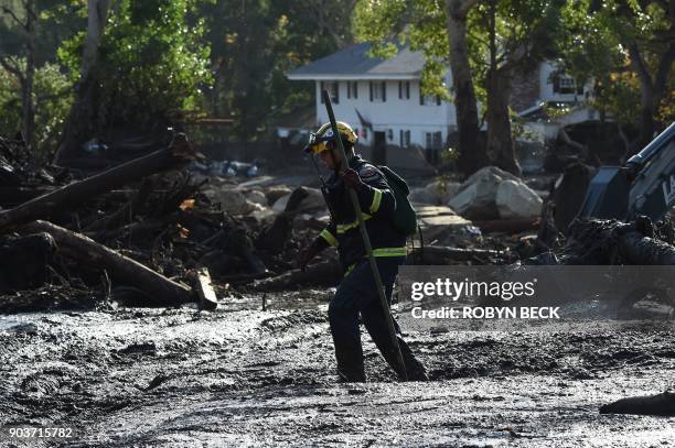 Member of the Orange County Fire Department Urban Search and Rescue walks in deep mud while searching for survivors amid the mud, debris and...