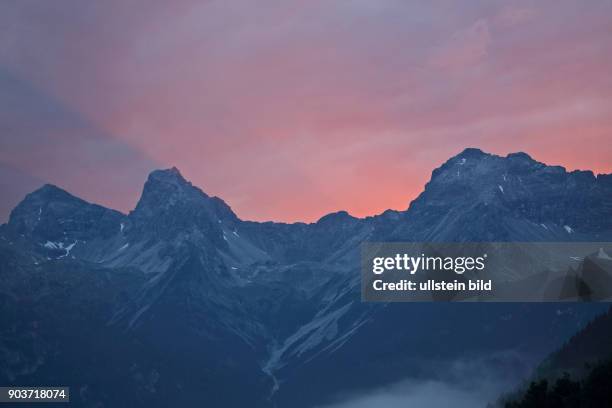 Abendstimmung Alpengluehn Berggipfel mit Wolken, Nebel und rotem Wolkenhimmel