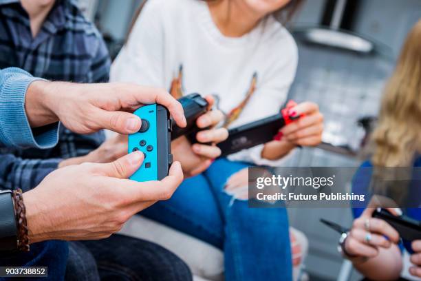 Detail of a group of men and women playing video games with a Nintendo Switch console and Joy Con wireless controllers, taken on March 7, 2017.