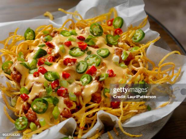 nacho style thin and crispy spiral fries with chili and cheese sauce - cheese sauce stock pictures, royalty-free photos & images