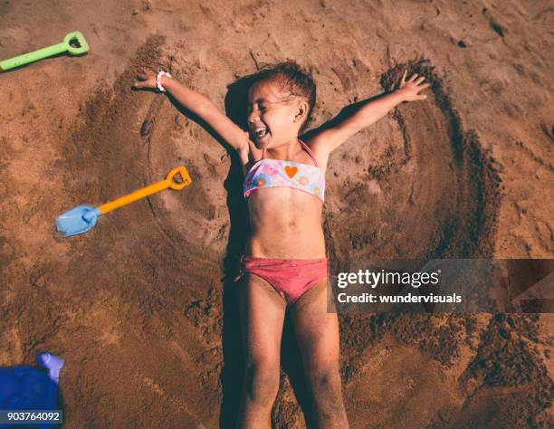 young asian girl making sand angel on beach in summer - angel island stock pictures, royalty-free photos & images