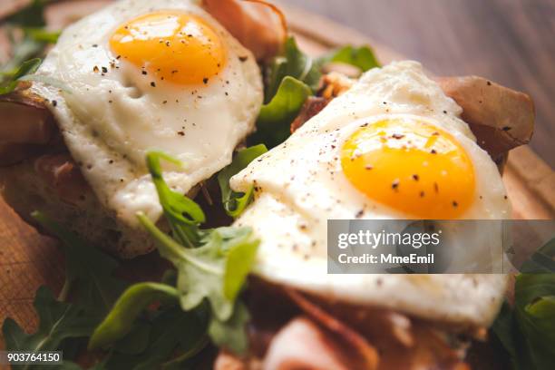 fried eggs sunny side up on baguette, ham and arugula - brunch imagens e fotografias de stock