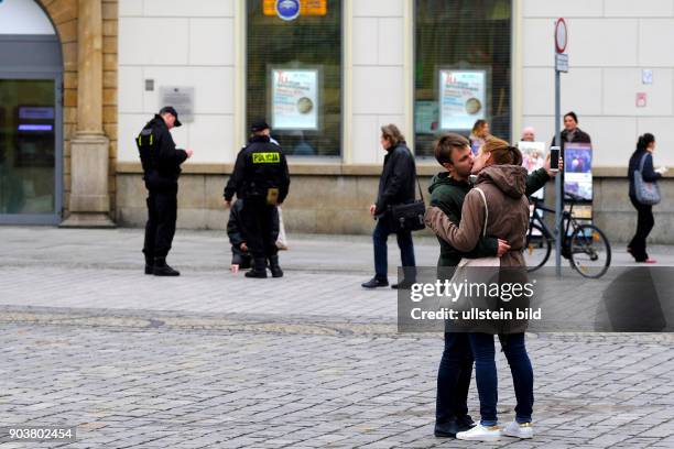 Küssendes Paar auf dem Rynek in der Altstadt. Im Hintergrund kontrollieren einen Bettler - Alltag in Wroclaw/Breslau