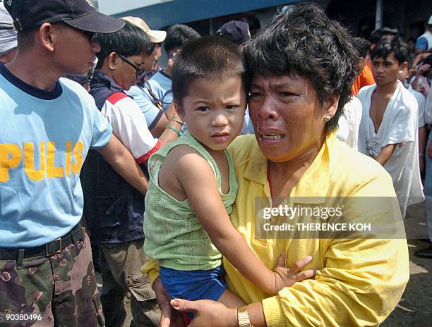 Mother clutching her child cries as she and other survivors of Superferry 9 arrive at the port of Zamboanga on September 6, 2009 after being rescued...