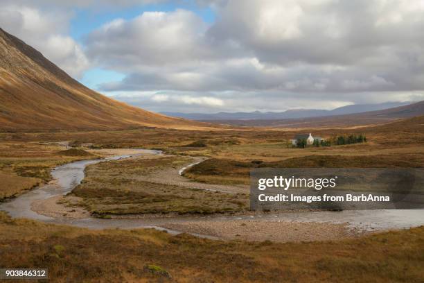 a remote cottage sits in glencoe valley, river and mountain landscape, scotland,uk - anna cabana - fotografias e filmes do acervo