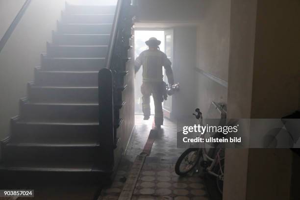Feuerwehrmann in einem verrauschen Treppenflur bei einem Wohnungsbrand in Berlin-Wedding