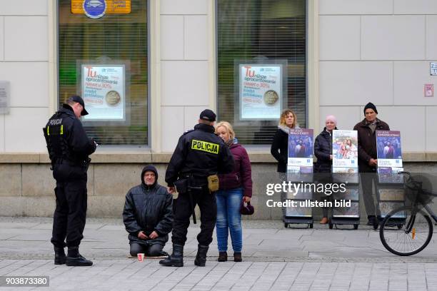 Polizisten auf dem Rynek in der Altstadt kontrollieren einen Bettler in Wroclaw/Breslau