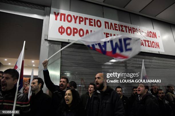 Communist-affiliated All-Workers Militant Front unionists chant slogans after setting up a banner reading "Ministry of foreclosures and tax thieves"...