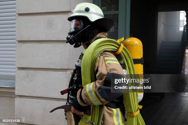 Feuerwehrmann ausgerüstet mit Atemschutzgerät, Maske, Schlauchpack mit Strahlrohr und der Feuerwehraxt bei einem Wohnungsbrand in Berlin-Wedding