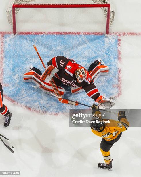 Eric Dop of the Bowling Green Falcons makes a glove save on Gavin Gould of the Michigan Tech Huskies tries to deflect the shot during the...