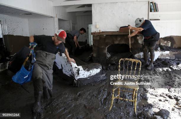 People dig through mud as they look for salvageable items in a the home of a family member that was destroyed by a mudslide on January 11, 2018 in...