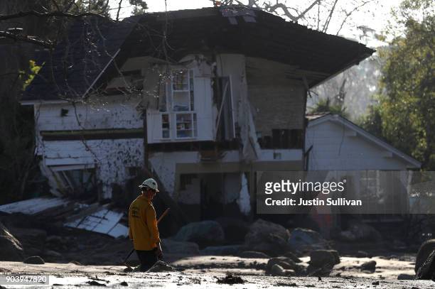 An urban search and rescue team member walks by a home that was destroyed by a mudslide on January 11, 2018 in Montecito, California. 17 people have...