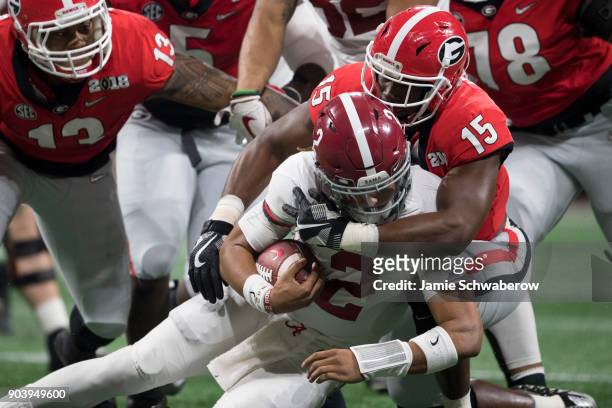 Andre Walker of the Georgia Bulldogs tackles Jalen Hurts of the Alabama Crimson Tide during the College Football Playoff National Championship held...