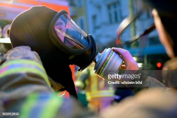 Feuerwehrmann rüstet sich während eines Wohnungsbrandes in der Bornholmer Strasse in Berlin-Prenzlauer Berg mit Atemschutzmaske und einem...