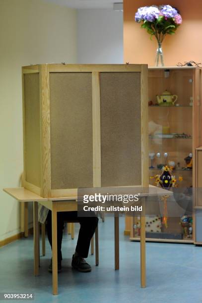 Wähler bei der Abstimmung in der Wahlkabine in einem Wahllokal in Berlin-Weißensee