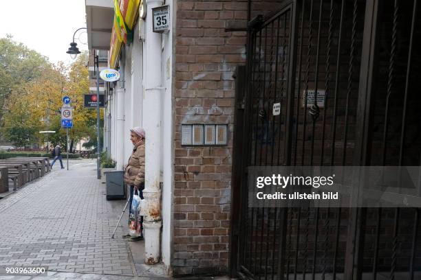 Alte Frau wartet vor einem Geschäft in Wroclaw/Breslau