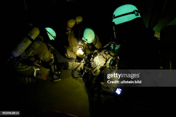 Fluoreszierende Feuerwehrhelme leuchten bei einer Übung der Atemschutznotfall trainierten Staffel der Feuerwache 1300 in den dunklen...