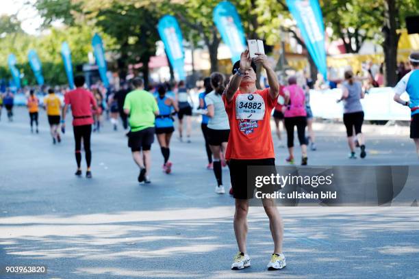 Läufer macht von sich mit dem Smartphone ein Selfie auf dem Berlin-Marathon 2016 entlang der Laufstrecke an