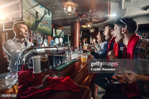 freunde sind das fußballspiel ansehen und trinken bier an der bar - kneipe stock-fotos und bilder