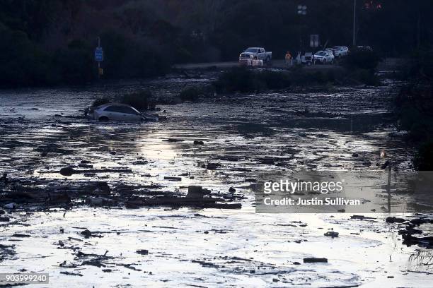 Car is submerged in muddy water in a flooded section of Highway 101 car on January 11, 2018 in Montecito, California. 17 people have died and...