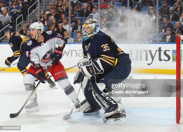 Jordan Schroeder of the Columbus Blue Jackets leaves a wake of ice spray as he stops in front of Linus Ullmark of the Buffalo Sabres during the...