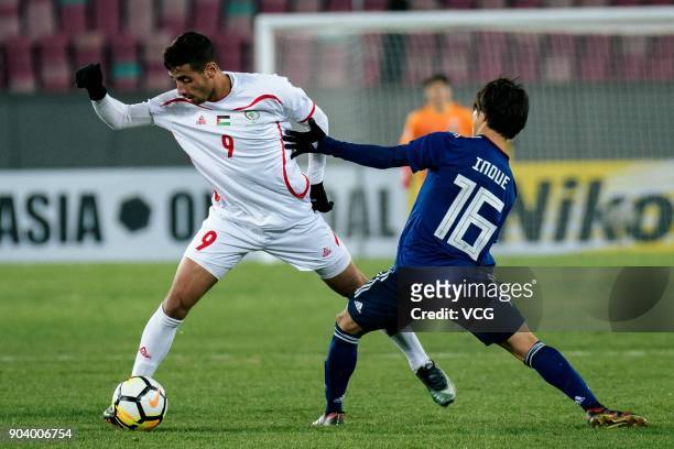 Shion Inoue of Japan and Oday Dabbagh of Palestine compete for the ball during the AFC U-23 Championship Group B match between Japan and Palestine at...