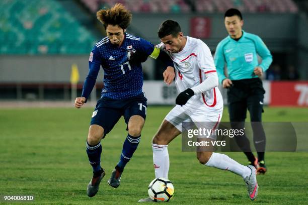 Yuta Kamiya of Japan and Oday Dabbagh of Palestine compete for the ball during the AFC U-23 Championship Group B match between Japan and Palestine at...