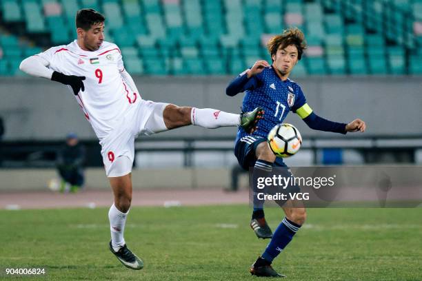 Yuta Kamiya of Japan and Oday Dabbagh of Palestine compete for the ball during the AFC U-23 Championship Group B match between Japan and Palestine at...