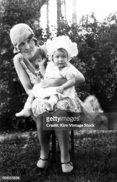 Flapper-styled woman with her daughter pose in the backyard.