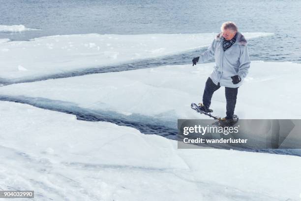 senior woman steps across ice floes in lake superior - seen great lakes stock pictures, royalty-free photos & images