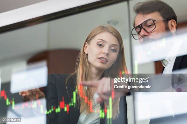 businesswoman and businessman talking profit on  futuristic display - stock market screen stock pictures, royalty-free photos & images