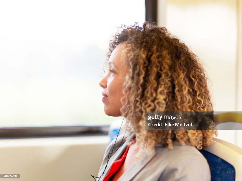 Woman with headphones on train looking out of the window
