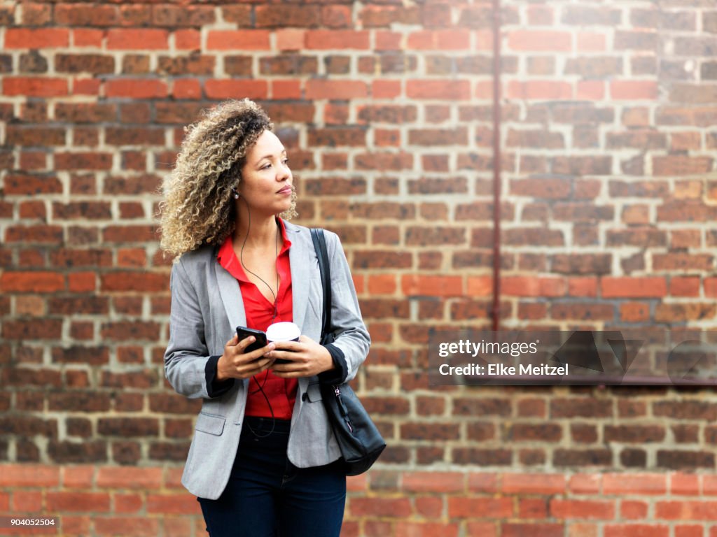 Woman with mobile phone and coffee waiting for the train