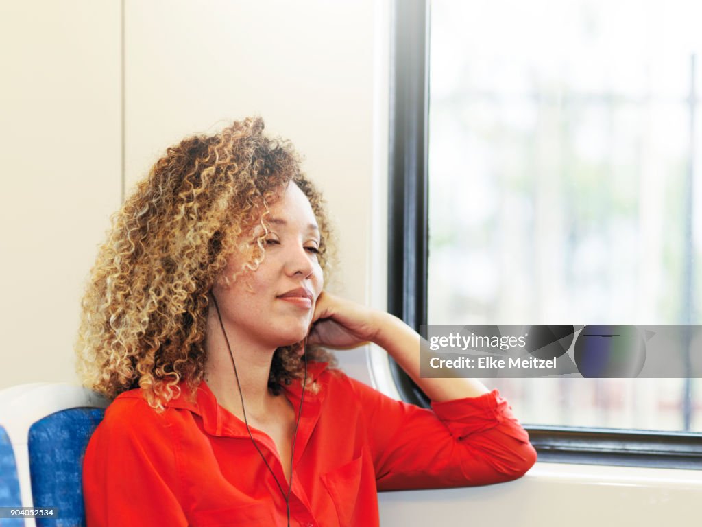Woman with headphones on train with her eyes closed