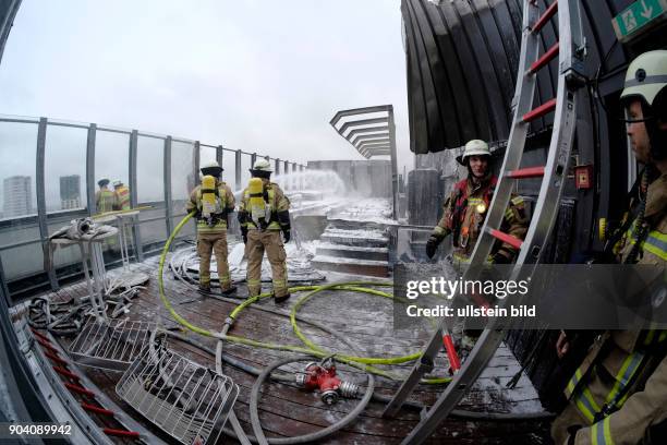 Einsatzkräfte der Berliner Feuerwehr bei Löscharbeiten auf dem Dach des Berliner Europa-Centers. Dort war eine Terasse auf dem Dach in Brand geraten