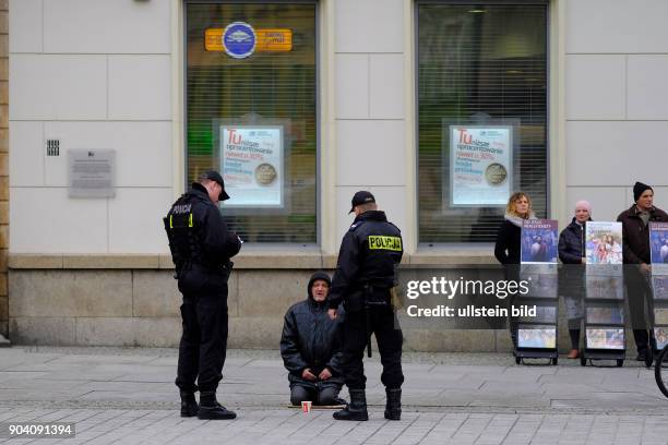 Polizisten auf dem Rynek in der Altstadt kontrollieren einen Bettler in Wroclaw/Breslau